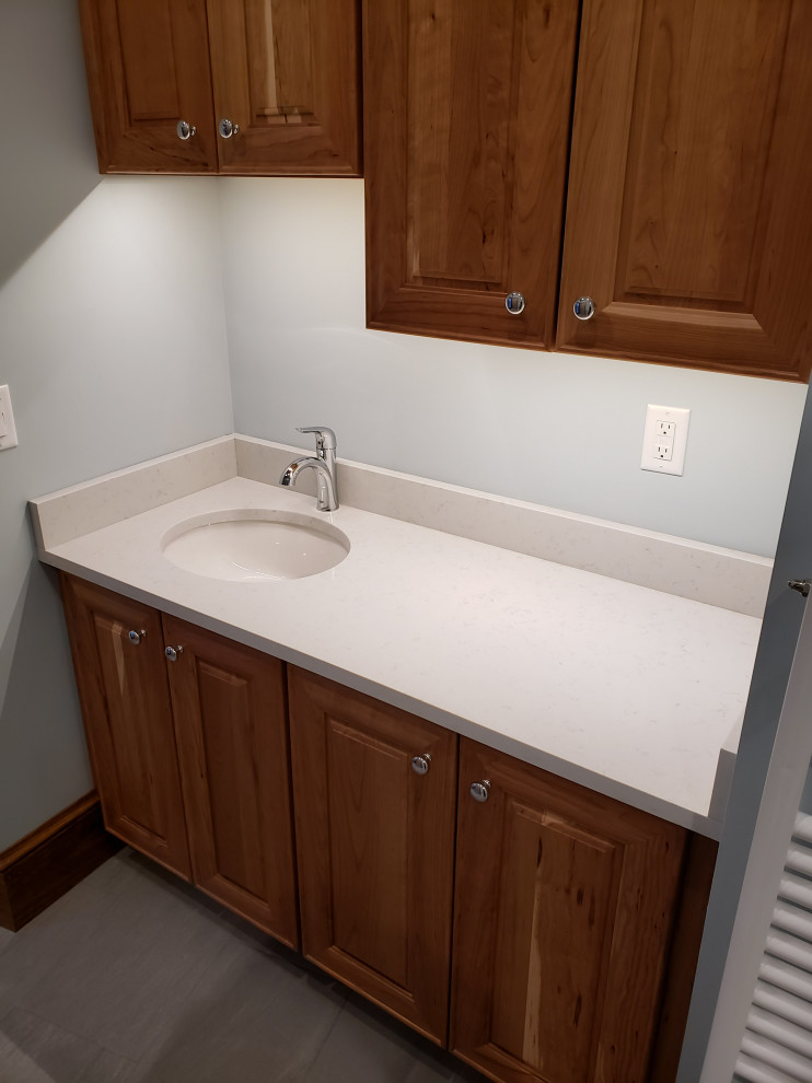 Example of a mid-sized trendy master white tile and marble tile ceramic tile, gray floor, double-sink and vaulted ceiling bathroom design in Boston with raised-panel cabinets, medium tone wood cabinets, a bidet, blue walls, an undermount sink, quartz countertops, a hinged shower door, white countertops and a built-in vanity