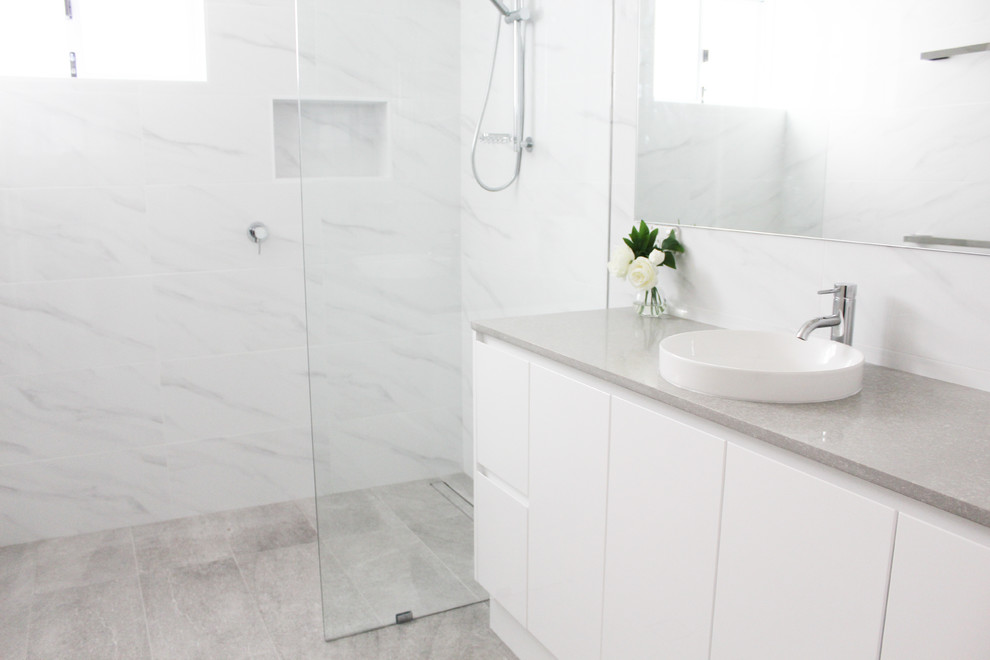 Exempel på ett mellanstort modernt grå grått en-suite badrum, med släta luckor, vita skåp, en öppen dusch, vit kakel, keramikplattor, vita väggar, klinkergolv i porslin, ett fristående handfat, bänkskiva i kvarts, grått golv och med dusch som är öppen