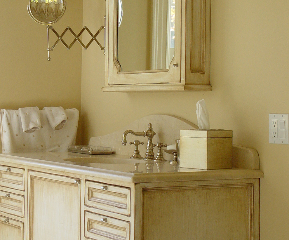 Immagine di una stanza da bagno padronale tradizionale con lavabo sottopiano, ante a filo, ante con finitura invecchiata, top in marmo, piastrelle beige e pareti beige