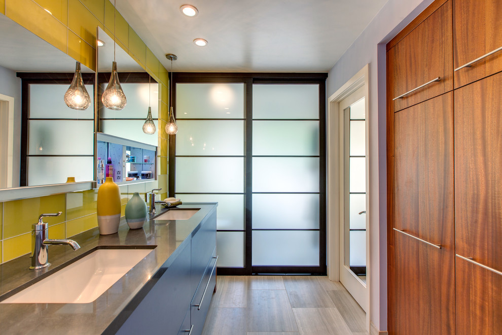 На фото: ванная комната в современном стиле с врезной раковиной, плоскими фасадами, желтой плиткой, стеклянной плиткой и серыми стенами с