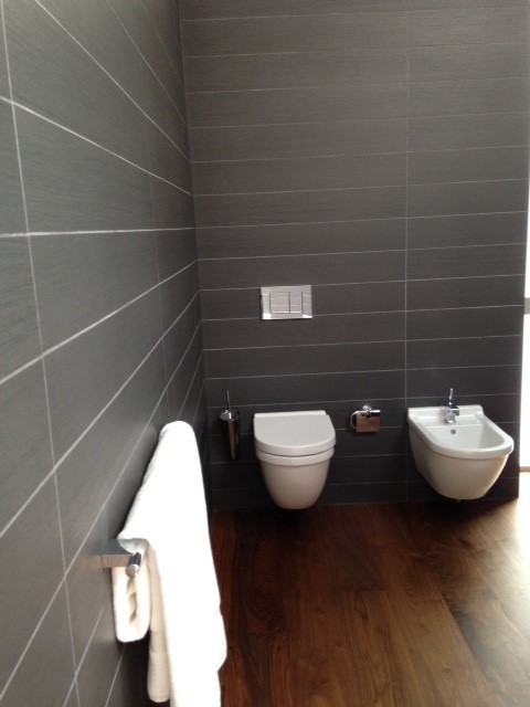 Идея дизайна: главная ванная комната среднего размера в современном стиле с инсталляцией, черной плиткой, черными стенами и паркетным полом среднего тона