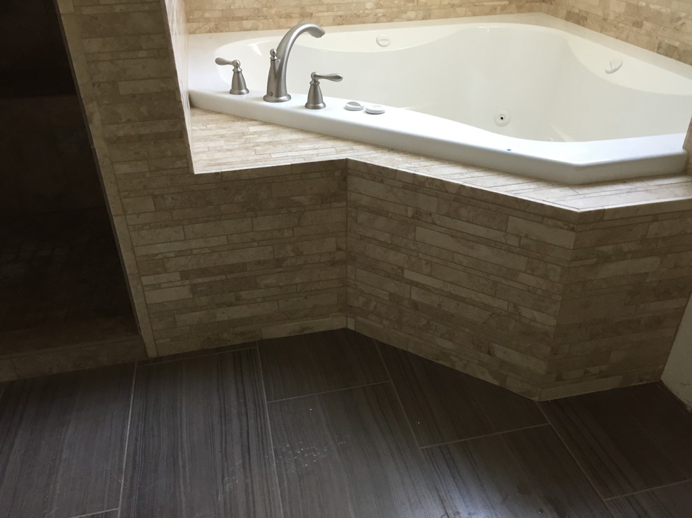 This is an example of a large rustic ensuite bathroom in Denver with a built-in bath, beige tiles, marble tiles, ceramic flooring and brown floors.