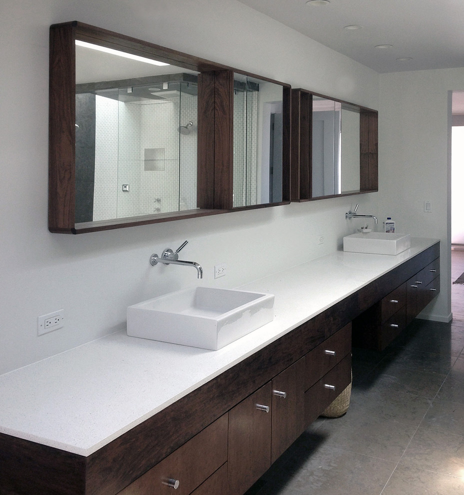 Exemple d'une très grande salle de bain rétro en bois foncé avec une vasque, un placard à porte plane, un plan de toilette en quartz modifié, un mur blanc, un sol en calcaire, un carrelage blanc, une baignoire d'angle, WC à poser et mosaïque.