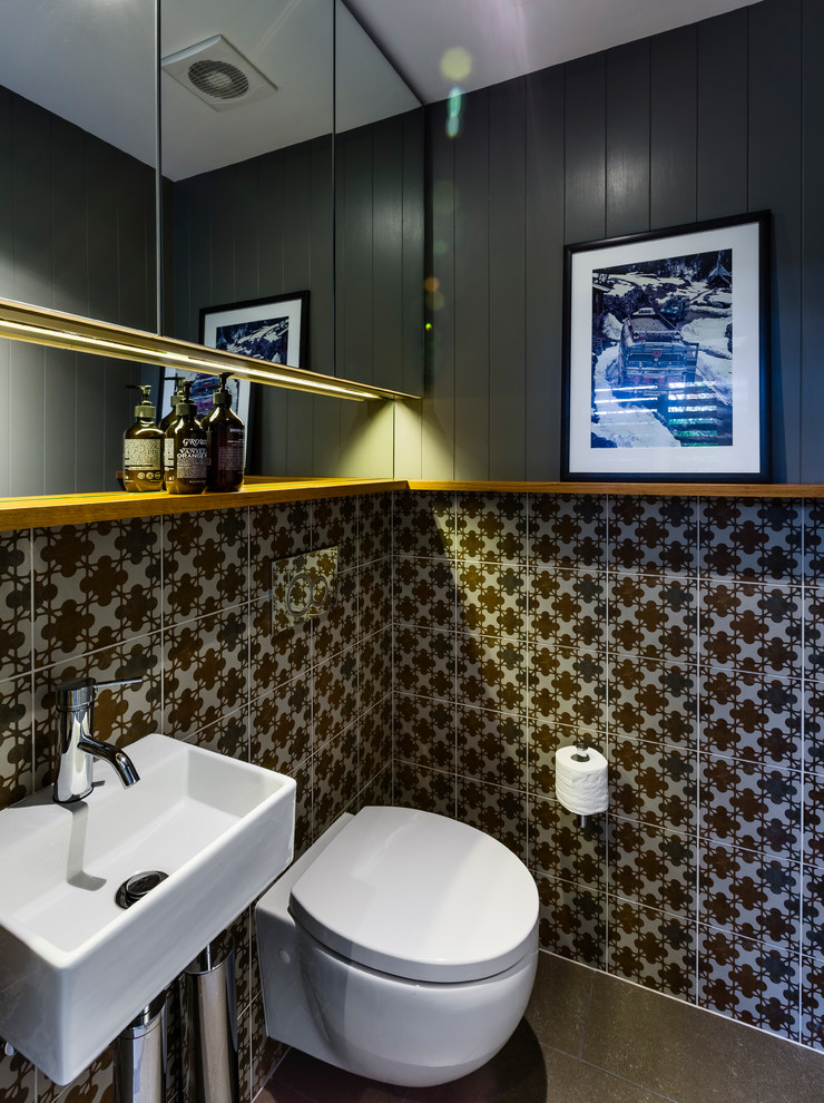 シドニーにあるお手頃価格の小さなコンテンポラリースタイルのおしゃれなトイレ・洗面所 (壁付け型シンク、壁掛け式トイレ、マルチカラーのタイル、磁器タイル、グレーの壁、セラミックタイルの床、木製洗面台) の写真