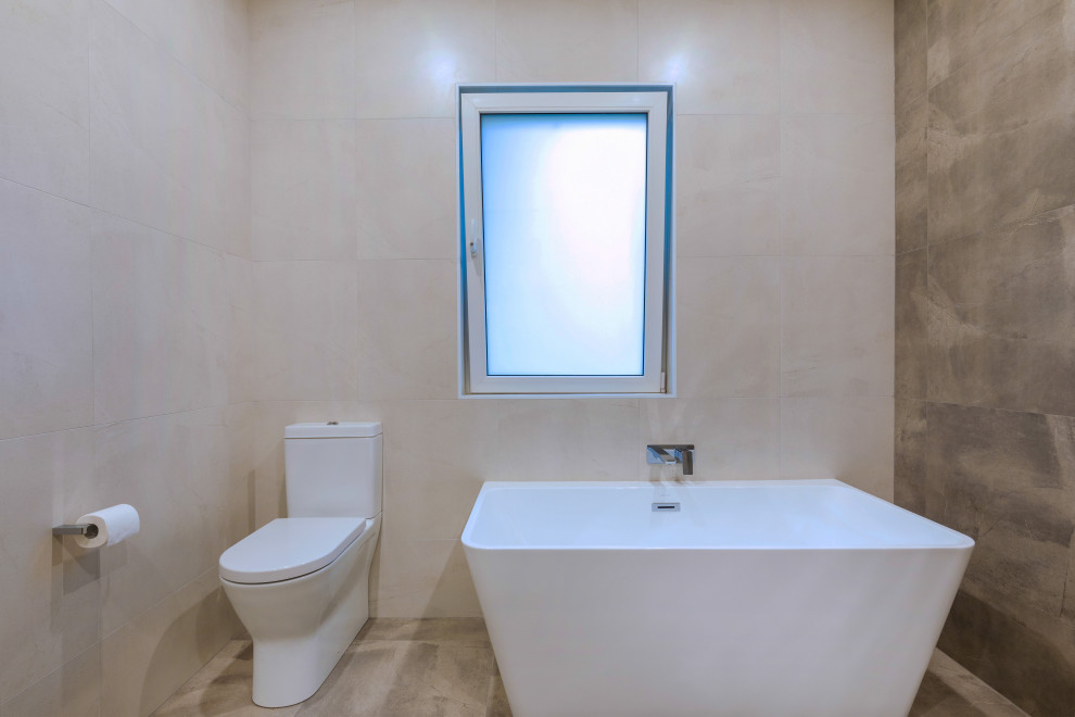 Exempel på ett stort modernt brun brunt en-suite badrum, med släta luckor, vita skåp, ett fristående badkar, en öppen dusch, en toalettstol med separat cisternkåpa, grå kakel, porslinskakel, vita väggar, klinkergolv i porslin, ett fristående handfat, träbänkskiva, grått golv och med dusch som är öppen