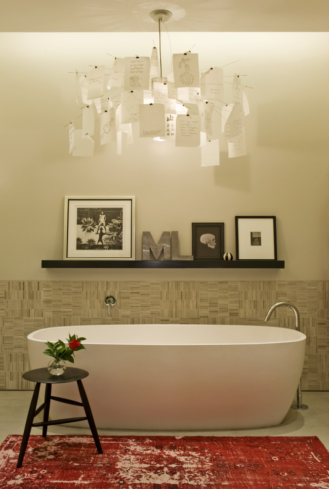 Foto på ett industriellt badrum, med ett fristående badkar, beige kakel och betonggolv