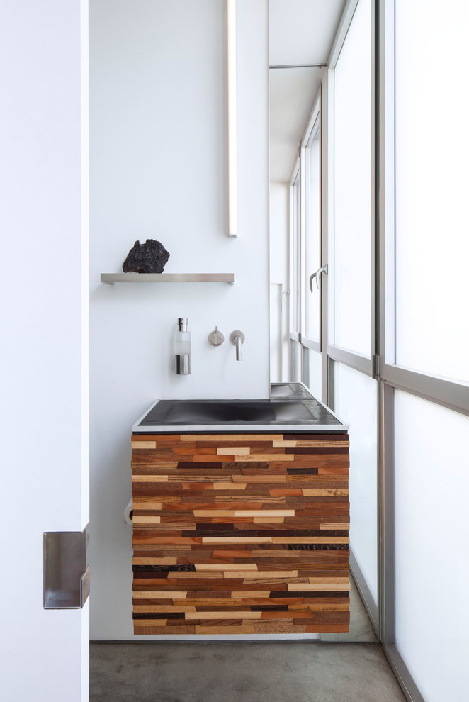 Cette photo montre une salle de bain tendance en bois brun avec un placard à porte plane, un mur blanc, sol en béton ciré, un plan vasque, un sol gris et meuble simple vasque.