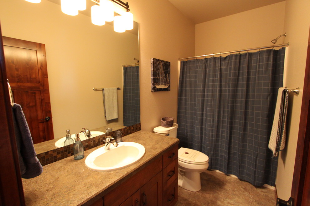 Bild på ett mellanstort amerikanskt badrum för barn, med ett nedsänkt handfat, släta luckor, skåp i mellenmörkt trä, laminatbänkskiva, ett badkar i en alkov, en toalettstol med separat cisternkåpa, brun kakel, beige väggar och vinylgolv