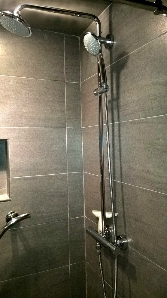 Immagine di una piccola stanza da bagno con doccia minimalista con doccia alcova, piastrelle grigie, piastrelle in ceramica e top in vetro