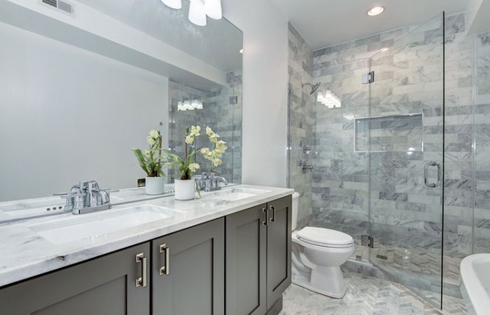 Réalisation d'une grande salle de bain principale avec un placard à porte shaker, des portes de placard grises, une baignoire indépendante, un carrelage gris, du carrelage en marbre et un plan de toilette en marbre.