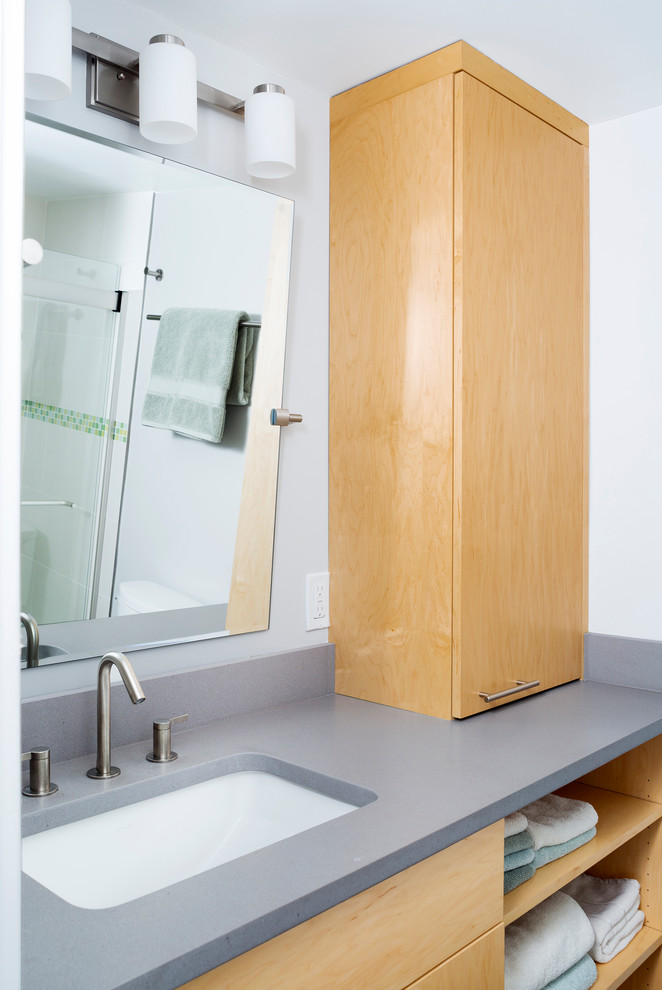 Aménagement d'une petite salle de bain contemporaine en bois clair avec un placard à porte plane, un carrelage bleu et un mur blanc.