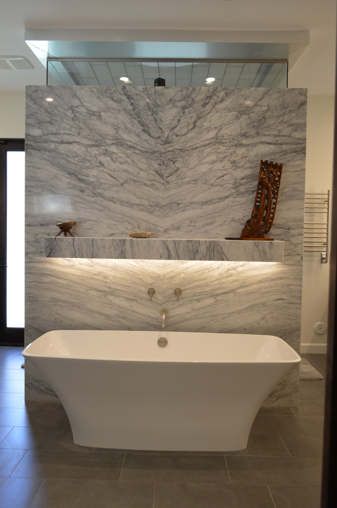 Inspiration pour une grande salle de bain principale design en bois foncé avec un lavabo encastré, un placard à porte plane, un plan de toilette en marbre, une baignoire indépendante, un carrelage gris, des carreaux de porcelaine, un mur beige et un sol en travertin.