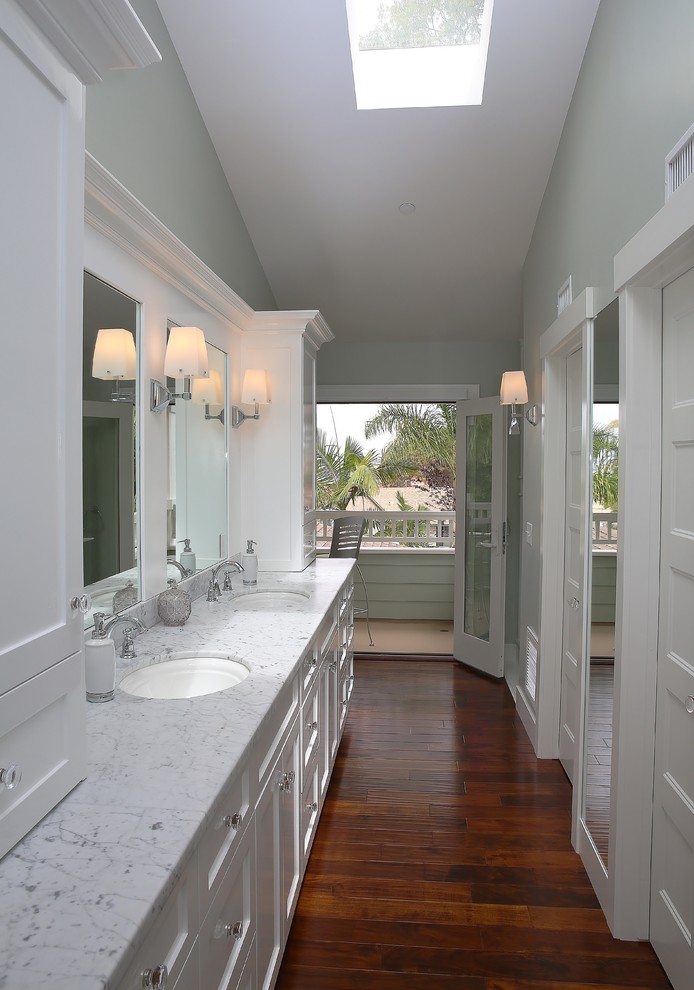 Mittelgroßes Klassisches Badezimmer En Suite mit Schrankfronten mit vertiefter Füllung, weißen Schränken, grüner Wandfarbe, dunklem Holzboden, Einbauwaschbecken, Marmor-Waschbecken/Waschtisch und braunem Boden in Orange County