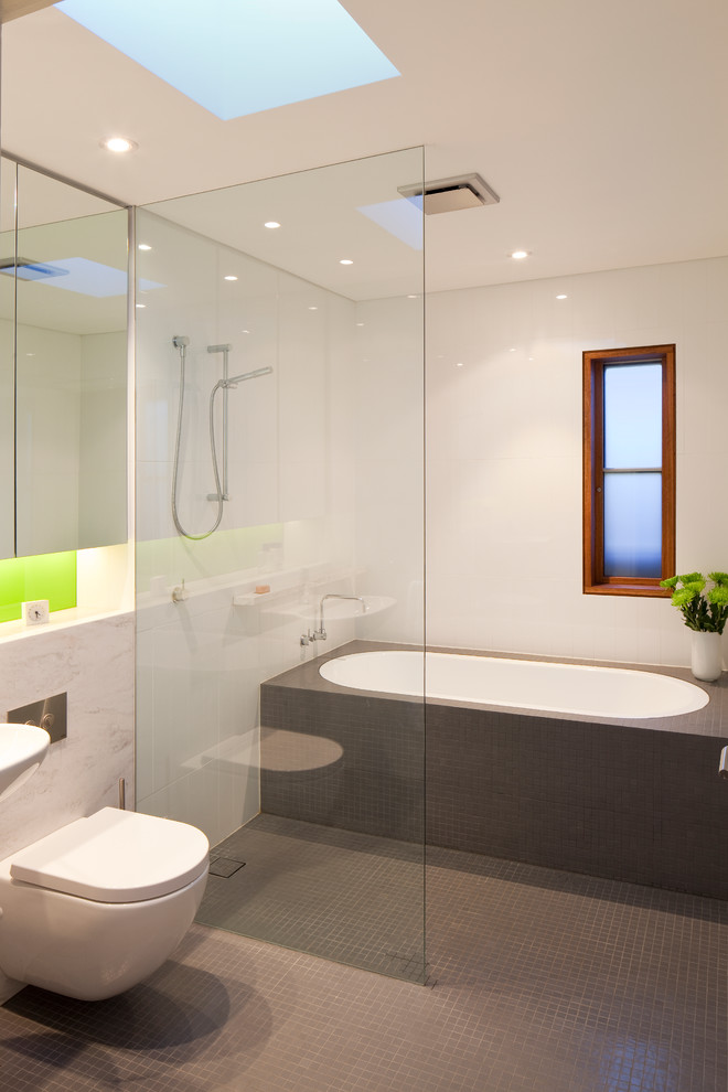 Photo of a contemporary bathroom in Sydney with a built-in bath, a wall mounted toilet and white walls.