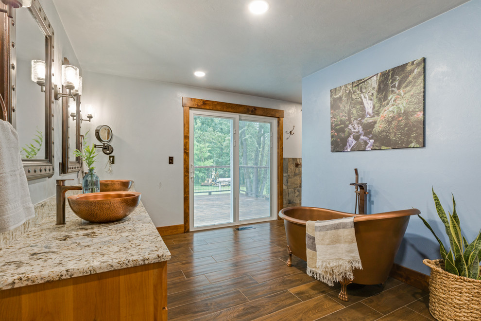 Ejemplo de cuarto de baño principal rústico grande con bañera exenta, paredes azules, lavabo sobreencimera, encimera de granito y ducha abierta