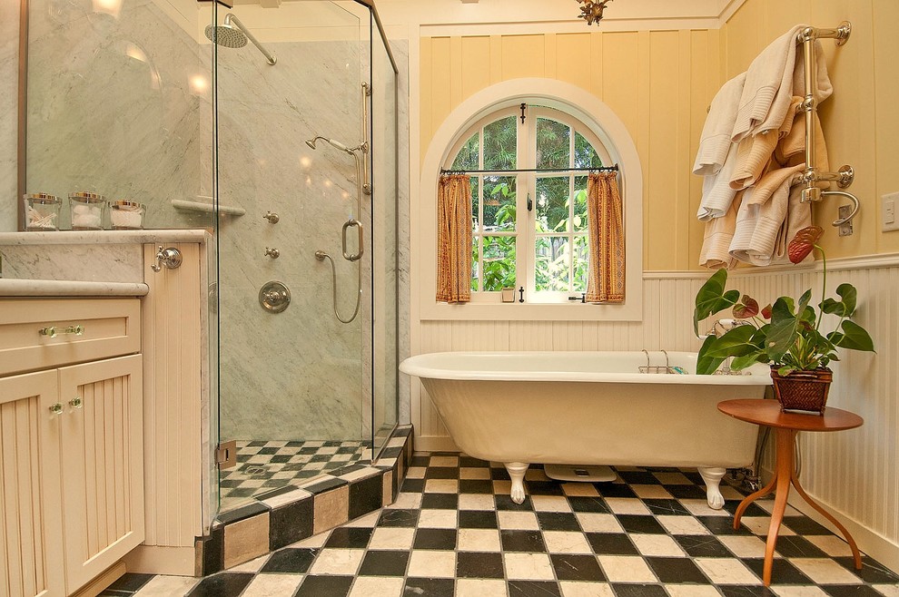 Inredning av ett klassiskt badrum, med ett badkar med tassar och flerfärgat golv