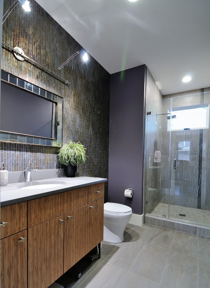 Cette image montre une salle de bain minimaliste en bois brun de taille moyenne avec un lavabo encastré, un placard à porte plane, un plan de toilette en quartz modifié, WC à poser, un carrelage gris, des carreaux de porcelaine, un mur violet et un sol en carrelage de porcelaine.