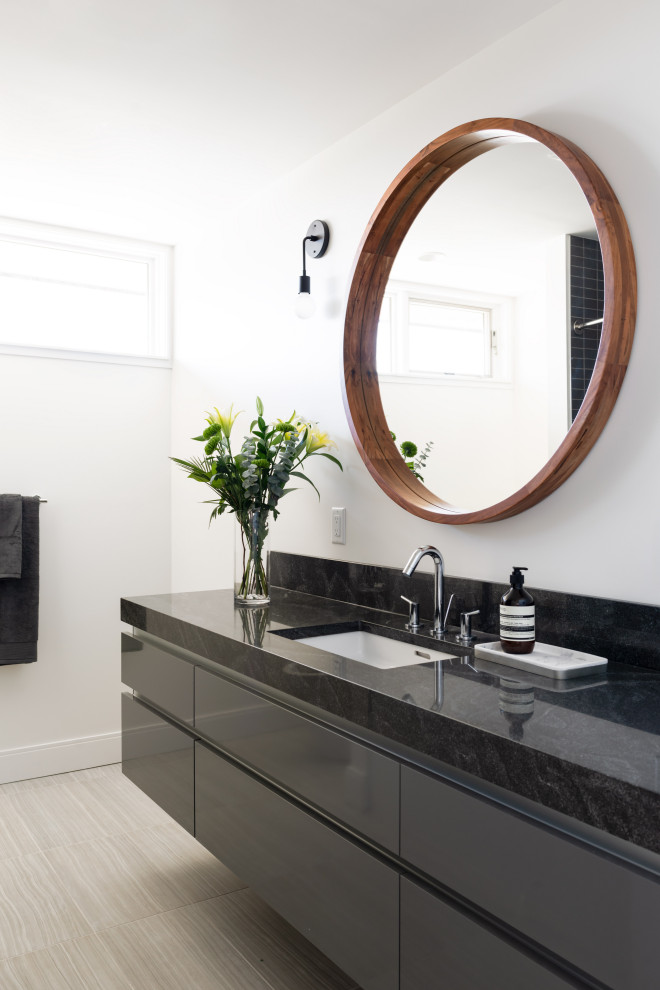 Modelo de cuarto de baño único y flotante contemporáneo con armarios con paneles lisos, puertas de armario negras, paredes blancas, lavabo bajoencimera, suelo gris y encimeras negras
