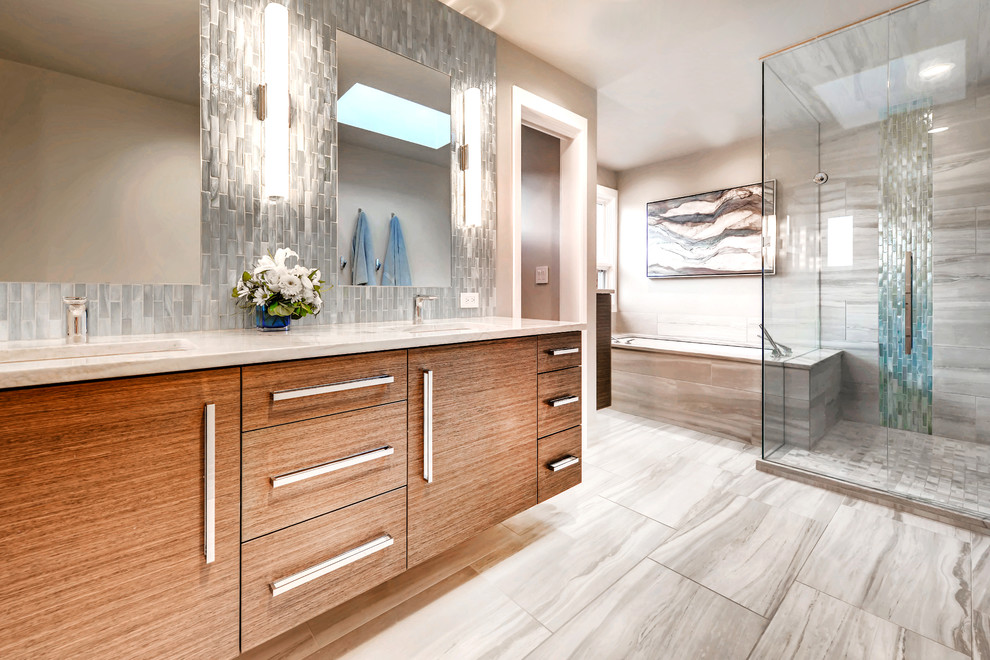 Cette photo montre une salle de bain principale tendance en bois brun avec un placard à porte plane, une baignoire encastrée, une douche d'angle, un carrelage gris, un lavabo encastré, un sol gris, une cabine de douche à porte battante et un plan de toilette beige.