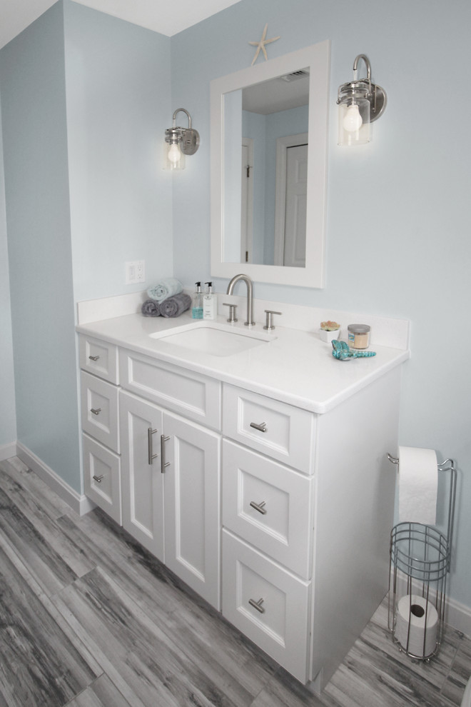 This is an example of a medium sized classic family bathroom in Boston with shaker cabinets, white cabinets, an alcove bath, a shower/bath combination, a two-piece toilet, grey tiles, porcelain tiles, blue walls, porcelain flooring, a submerged sink, engineered stone worktops, grey floors, a sliding door and white worktops.