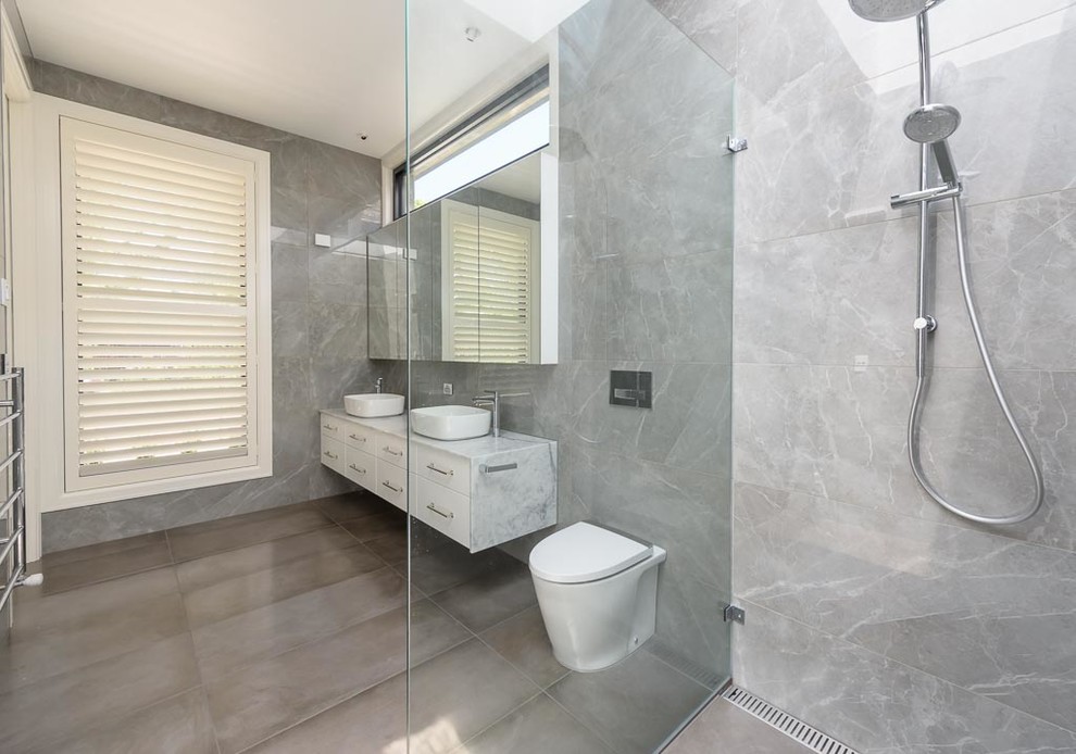 Idéer för ett stort modernt flerfärgad badrum, med släta luckor, vita skåp, en öppen dusch, en toalettstol med hel cisternkåpa, grå kakel, porslinskakel, grå väggar, klinkergolv i porslin, ett fristående handfat, marmorbänkskiva, grått golv och med dusch som är öppen