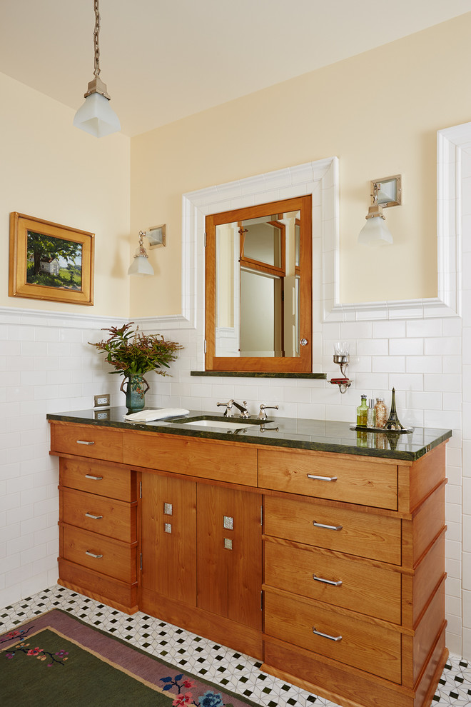 Exemple d'une salle de bain craftsman en bois brun avec un lavabo encastré, un carrelage blanc, un mur jaune, un sol en carrelage de céramique, un placard à porte plane, un carrelage métro, un plan de toilette en granite et un plan de toilette vert.