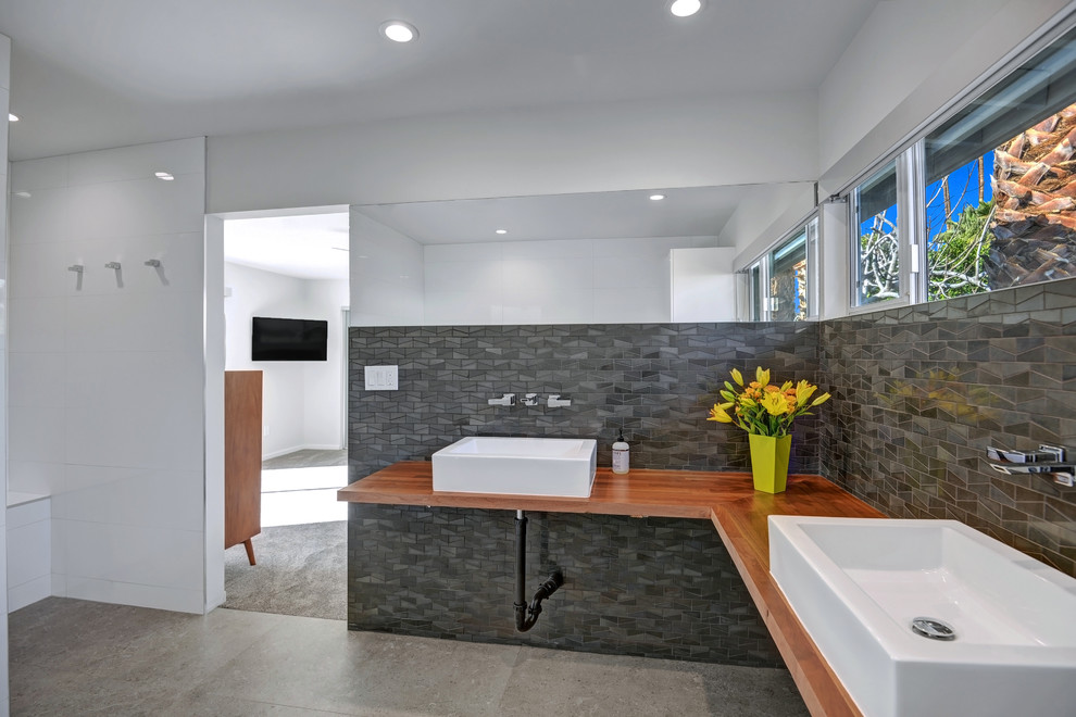 Идея дизайна: главная ванная комната среднего размера в стиле ретро с плоскими фасадами, белыми фасадами, душем без бортиков, серой плиткой, каменной плиткой, белыми стенами, полом из керамогранита, настольной раковиной и столешницей из дерева