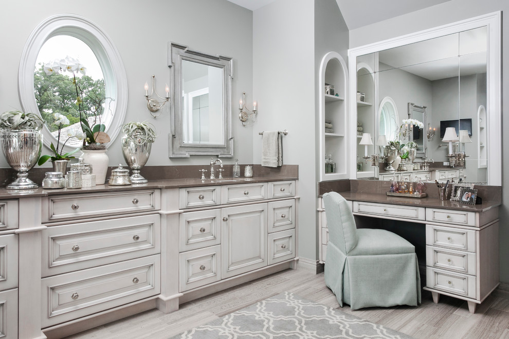 Ejemplo de cuarto de baño principal clásico con lavabo bajoencimera, armarios con paneles con relieve, paredes grises y puertas de armario blancas