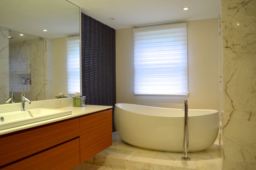 Inspiration for a large contemporary ensuite bathroom in Miami with flat-panel cabinets, medium wood cabinets, a freestanding bath, grey tiles, white tiles, marble tiles, white walls, marble flooring, a trough sink, solid surface worktops and white floors.