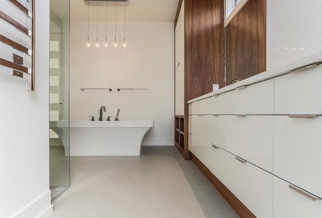 Modernes Badezimmer En Suite mit flächenbündigen Schrankfronten, dunklen Holzschränken und freistehender Badewanne in Calgary