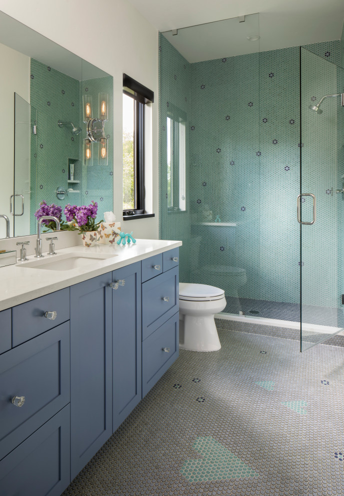 Идея дизайна: ванная комната в стиле кантри с фасадами в стиле шейкер, синими фасадами, душем в нише, зеленой плиткой, плиткой мозаикой, белыми стенами, полом из мозаичной плитки, душевой кабиной, врезной раковиной, разноцветным полом, душем с распашными дверями, белой столешницей и встроенной тумбой