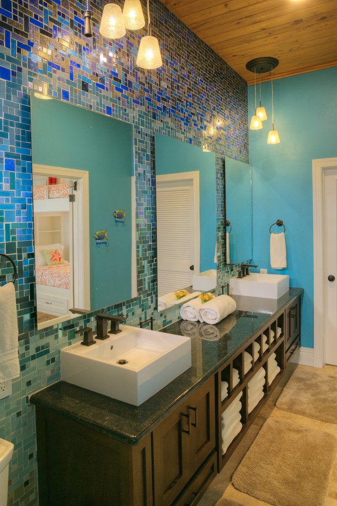 На фото: огромная главная ванная комната в современном стиле с фасадами в стиле шейкер, темными деревянными фасадами, открытым душем, раздельным унитазом, синей плиткой, стеклянной плиткой, синими стенами, полом из травертина, накладной раковиной, столешницей из гранита, бежевым полом, открытым душем и черной столешницей с