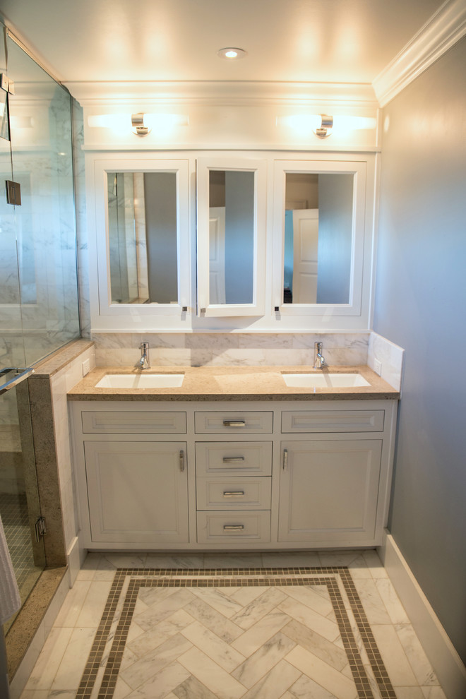 Photo of a classic ensuite bathroom in San Diego with a submerged sink, recessed-panel cabinets, white cabinets, limestone worktops, stone tiles, grey walls and marble flooring.