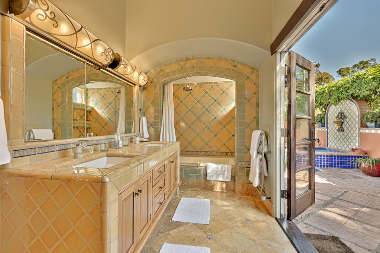 Mittelgroßes Mediterranes Badezimmer En Suite mit hellen Holzschränken, Badewanne in Nische, Duschbadewanne, gelben Fliesen, Keramikfliesen, Travertin, Unterbauwaschbecken, gefliestem Waschtisch und Duschvorhang-Duschabtrennung in San Diego