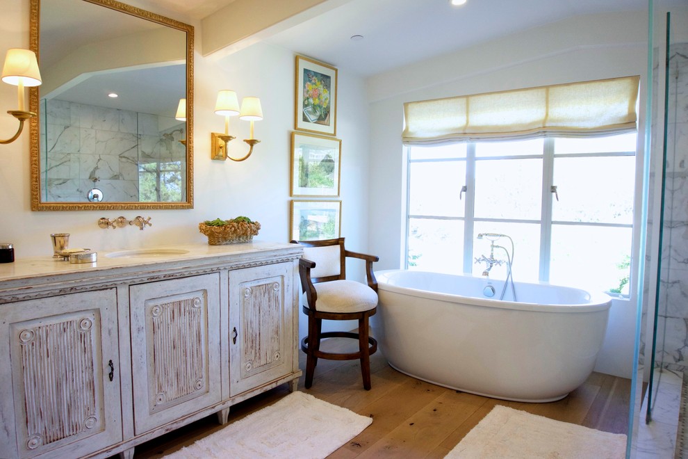 Lantlig inredning av ett mellanstort en-suite badrum, med möbel-liknande, vita skåp, ett fristående badkar, en öppen dusch, vit kakel, stenkakel, vita väggar, klinkergolv i terrakotta, ett undermonterad handfat och marmorbänkskiva