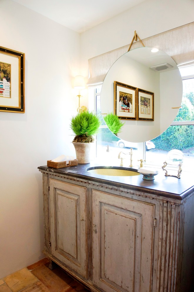 Cette image montre une petite salle d'eau rustique en bois vieilli avec un placard en trompe-l'oeil, un mur beige, tomettes au sol, un lavabo encastré et un plan de toilette en marbre.