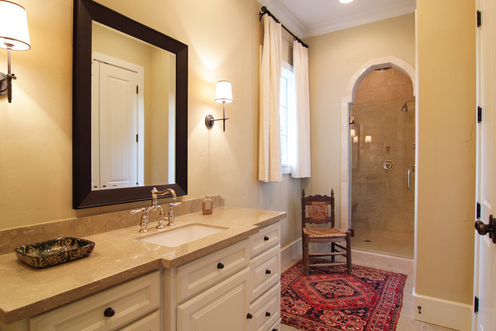 Свежая идея для дизайна: главная ванная комната среднего размера в средиземноморском стиле с фасадами с выступающей филенкой, белыми фасадами, столешницей из известняка, отдельно стоящей ванной, бежевой плиткой и каменной плиткой - отличное фото интерьера