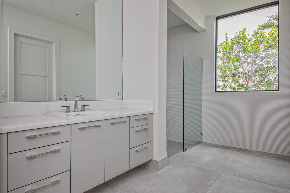 Inspiration for a large modern ensuite bathroom in Miami with white walls, concrete flooring, grey floors, flat-panel cabinets, grey cabinets, a freestanding bath, a built-in shower, a built-in sink, marble worktops, an open shower and white worktops.