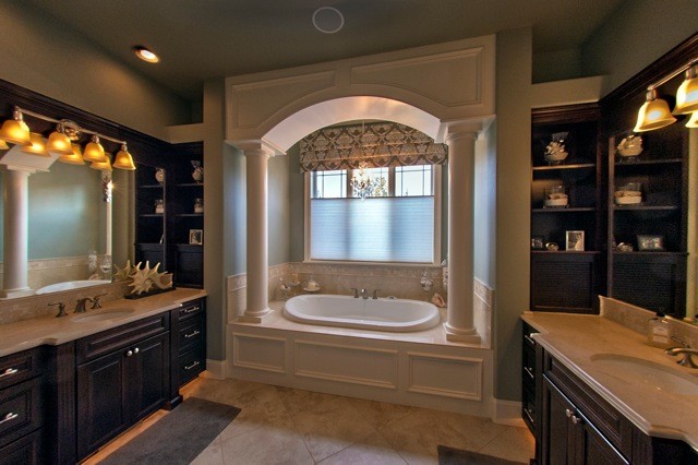 This is an example of a large mediterranean ensuite bathroom in Seattle with recessed-panel cabinets, brown cabinets, a built-in bath, a walk-in shower, a one-piece toilet, multi-coloured tiles, mosaic tiles, green walls, porcelain flooring, a submerged sink, marble worktops, beige floors and a hinged door.