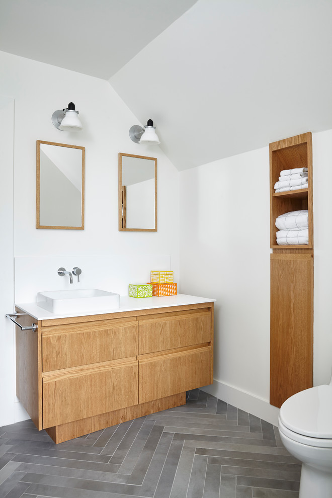 Idéer för mellanstora minimalistiska vitt badrum med dusch, med släta luckor, skåp i ljust trä, vita väggar, grått golv, en dusch i en alkov, en toalettstol med hel cisternkåpa, vit kakel, keramikplattor, klinkergolv i keramik, ett nedsänkt handfat, bänkskiva i akrylsten och dusch med gångjärnsdörr