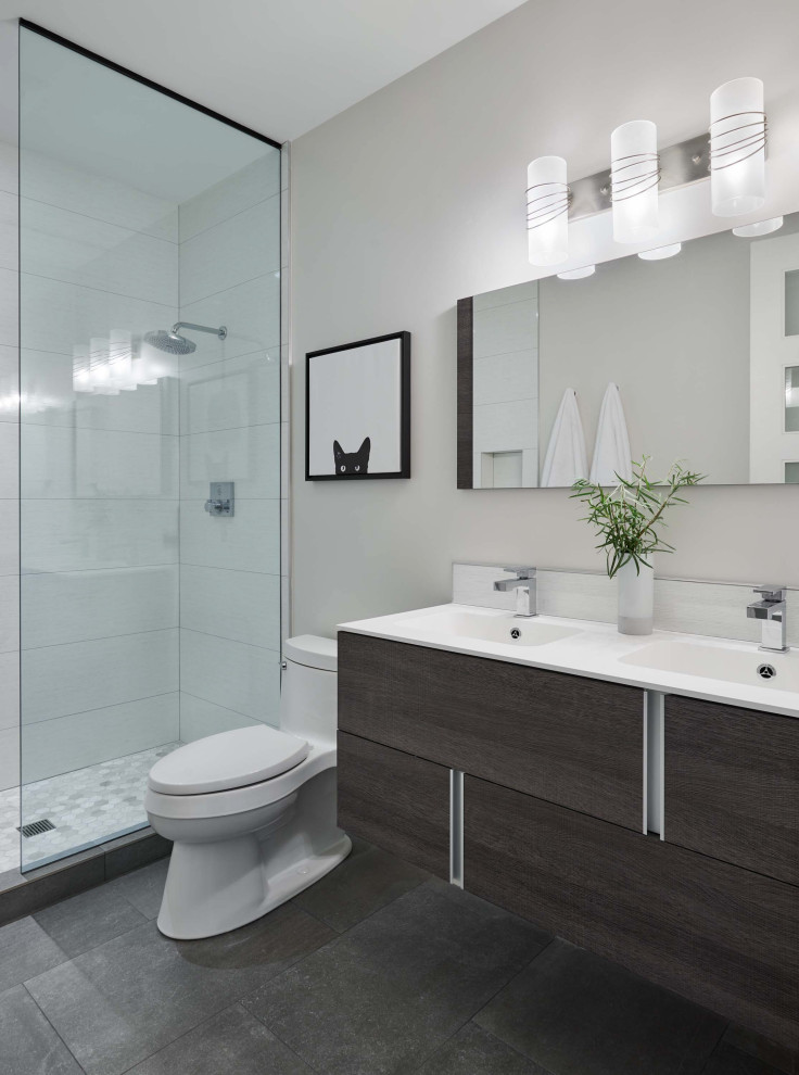 Exempel på ett mellanstort modernt vit vitt badrum, med släta luckor, skåp i mörkt trä, en dusch i en alkov, en toalettstol med separat cisternkåpa, grå kakel, porslinskakel, grå väggar, betonggolv, ett integrerad handfat, bänkskiva i akrylsten, grått golv och med dusch som är öppen