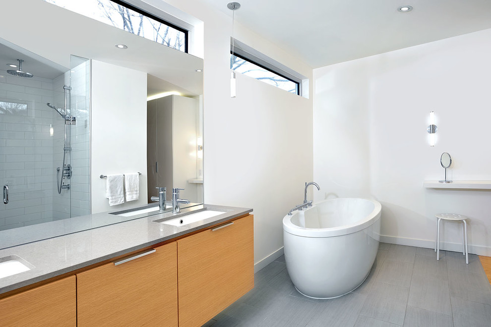 Cette image montre une salle de bain design avec une baignoire indépendante, un lavabo encastré et un plan de toilette gris.