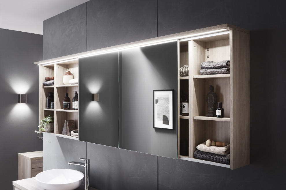 Foto på ett mellanstort funkis en-suite badrum, med släta luckor, skåp i ljust trä, ett hörnbadkar, grå kakel, kakelplattor, ett fristående handfat och laminatbänkskiva