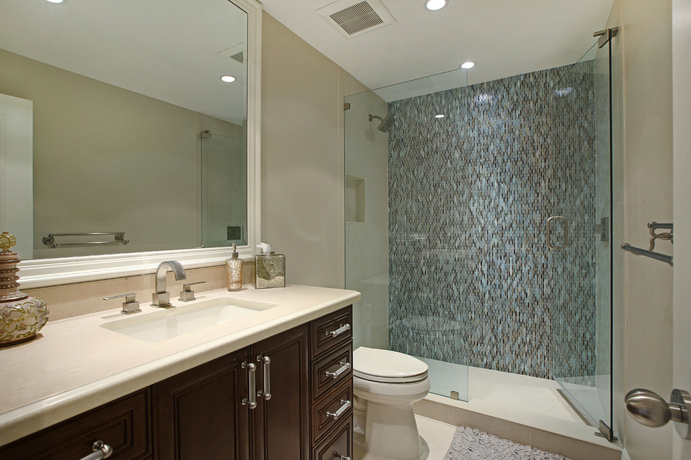 Elegant blue tile and mosaic tile alcove shower photo in Miami with an undermount sink, raised-panel cabinets, dark wood cabinets and beige walls