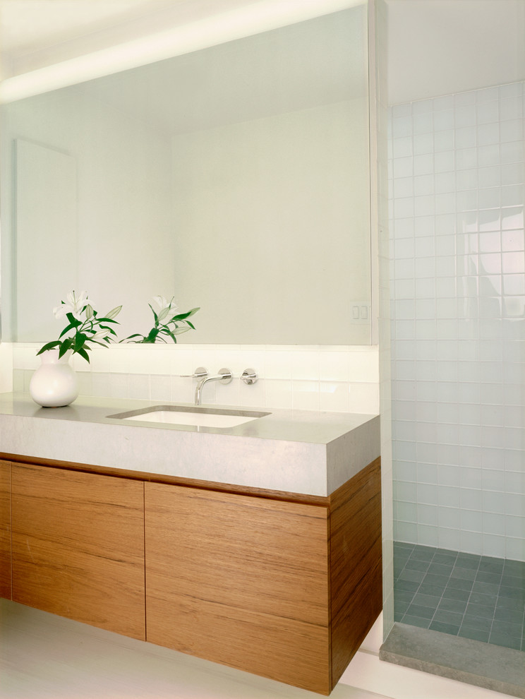 Inspiration for a small modern bathroom in New York with a submerged sink, flat-panel cabinets, medium wood cabinets, limestone worktops, a walk-in shower, a wall mounted toilet, white tiles, glass tiles, slate flooring and white walls.