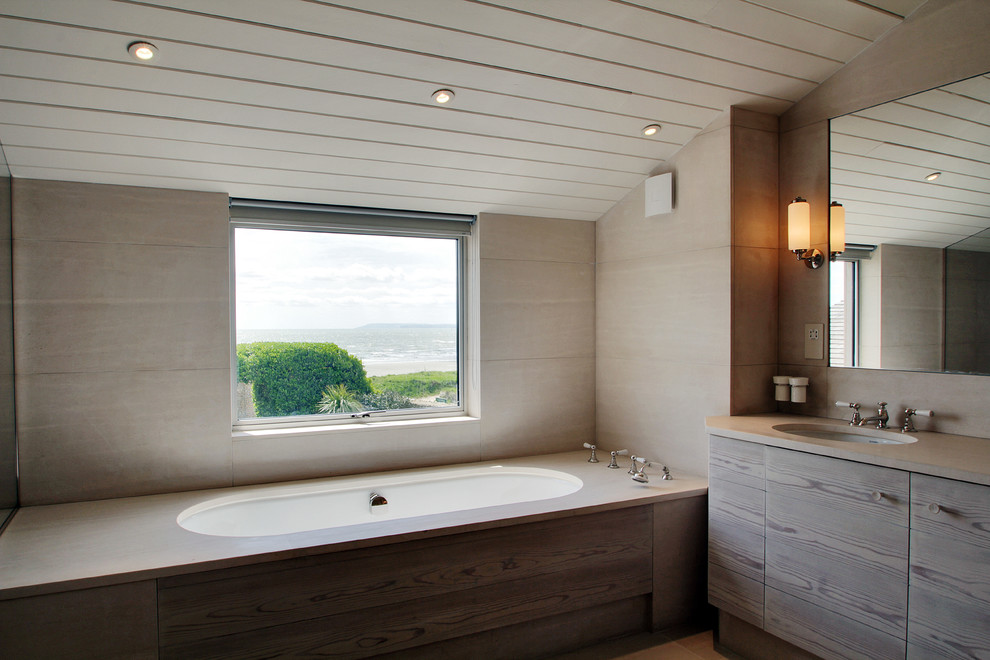 This is an example of a coastal bathroom in Sussex with flat-panel cabinets and an alcove bath.