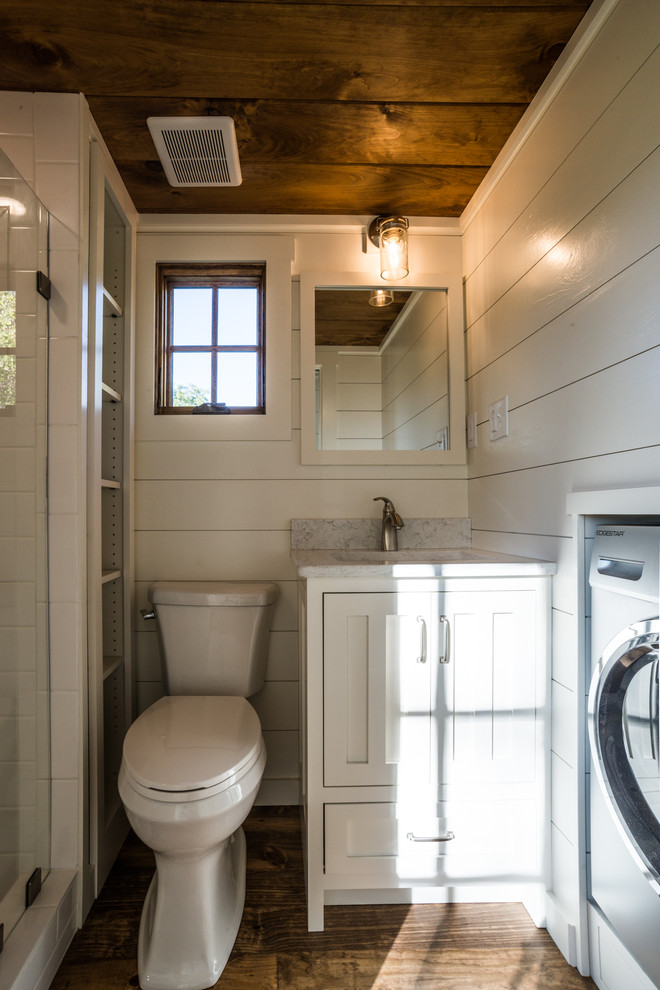 Bild på ett lantligt badrum, med möbel-liknande, vita skåp, en öppen dusch, en toalettstol med separat cisternkåpa, vit kakel, tunnelbanekakel, vita väggar, mörkt trägolv, ett undermonterad handfat, bänkskiva i kvartsit, brunt golv och dusch med gångjärnsdörr
