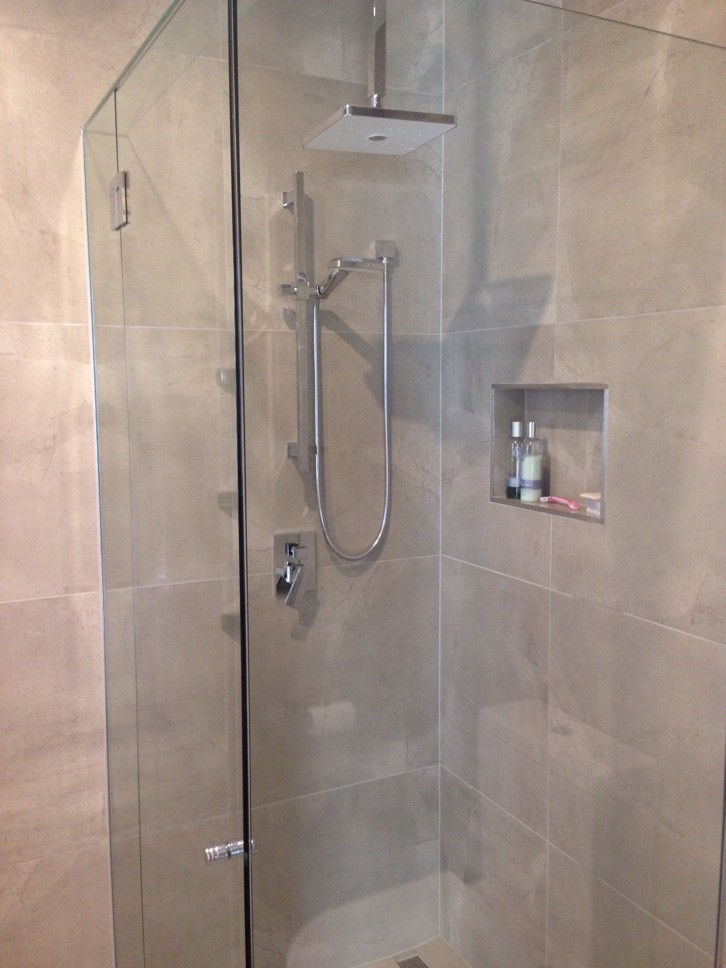 Cette image montre une petite salle de bain design avec une vasque, des portes de placard blanches, une douche à l'italienne, WC séparés, un carrelage beige et un mur beige.