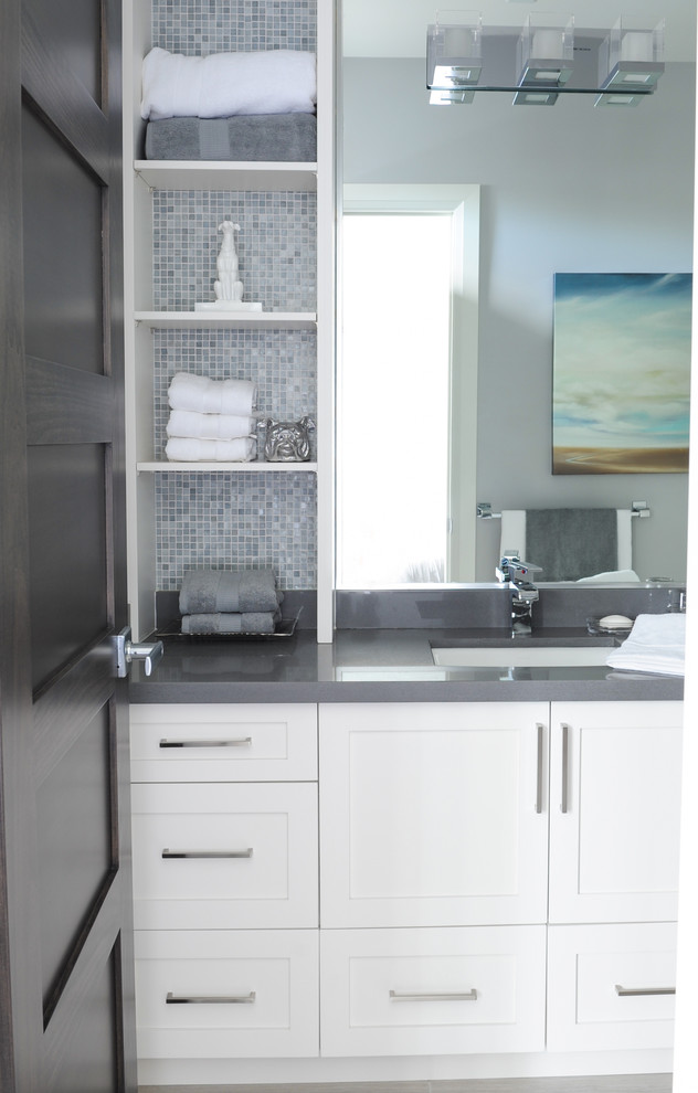 Modelo de cuarto de baño tradicional renovado con armarios estilo shaker, puertas de armario blancas, baldosas y/o azulejos grises, baldosas y/o azulejos en mosaico, paredes grises y lavabo bajoencimera