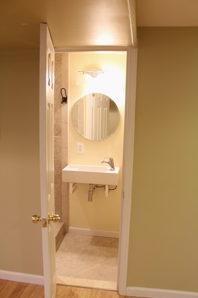 Modern inredning av ett litet badrum, med ett väggmonterat handfat, en hörndusch, en toalettstol med separat cisternkåpa, beige kakel, keramikplattor, gula väggar och klinkergolv i keramik